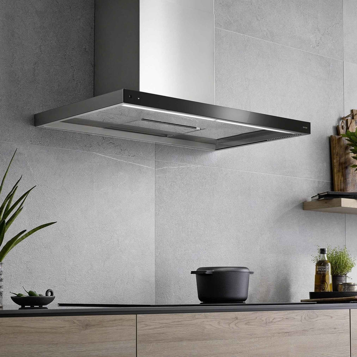 Berbel Wandhaube Glassline BWH GL in Schwarz über einem Kochfeld in moderner Küche mit grauer Steinoptik und integrierter LED-Beleuchtung.