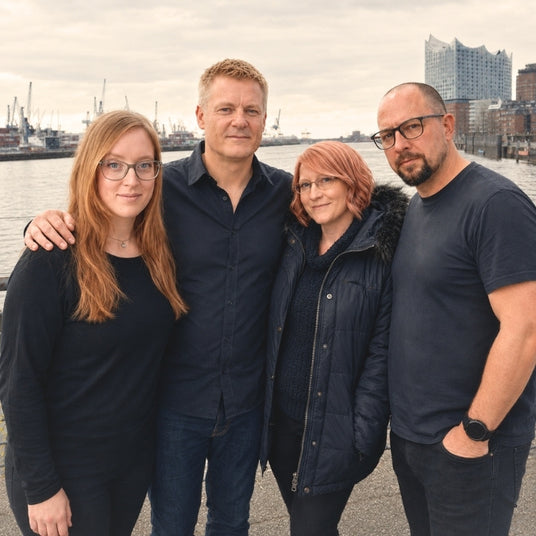 Das Team von Nordsee-Küchen GmbH posiert gemeinsam vor der Hamburger Hafenkulisse mit der Elbphilharmonie im Hintergrund. Die Gruppe, bestehend aus vier Fachleuten, vermittelt ein Bild von Professionalität und persönlichem Service für den Online-Shop Dunstabzugshauben-Welt.