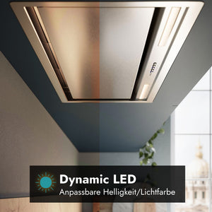 Unteransicht des Falmec Lüfterbausteins Plus Green Tech mit integrierter LED-Beleuchtung, die durch einen vertikalen Farbverlauf unterschiedliche Lichttemperaturen und Helligkeiten demonstriert. Im unteren Bereich zeigt ein schwarzes Grafik-Overlay den Text "Dynamic LED" sowie den Untertitel "Anpassbare Helligkeit/Lichtfarbe" und ein hellblaues Sonnensymbol.