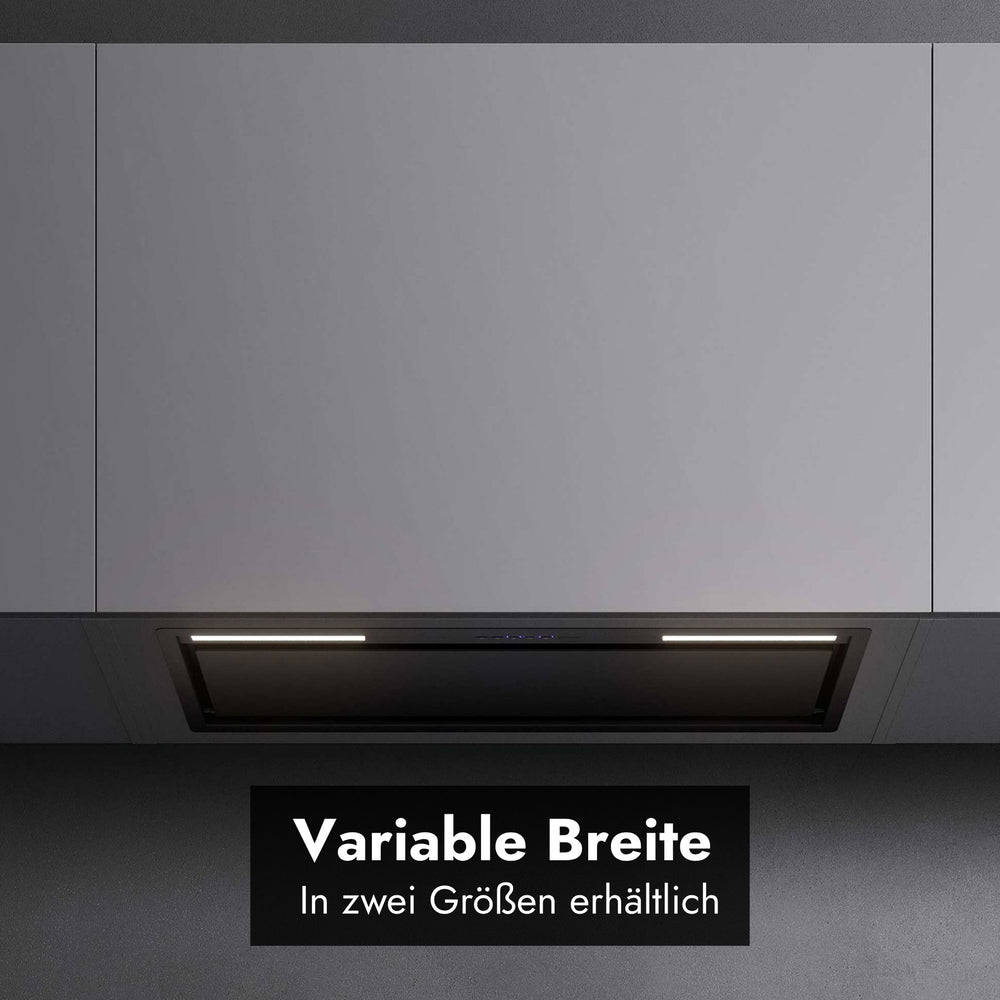 Frontale Detailansicht des bündig integrierten Falmec Lüfterbausteins Plus Green Tech unter glatten, hellgrauen Oberschränken mit aktivierter LED-Beleuchtung. Im unteren Bereich zeigt ein schwarzes Grafik-Overlay den Text "Variable Breite" sowie den Untertitel "In zwei Größen erhältlich".