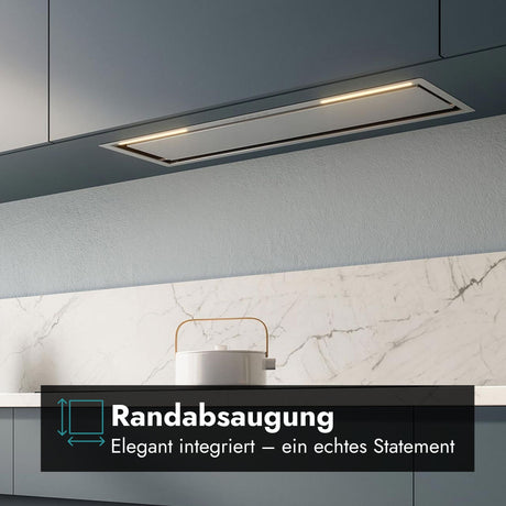 Nahaufnahme des Falmec Lüfterbausteins Plus Green Tech, bündig integriert in dunkelgraue Oberschränke. Die Dunstabzugshaube verfügt über eine helle LED-Beleuchtung und ist über einem Induktionskochfeld mit einem weißen Topf positioniert. Unten rechts befindet sich ein Grafik-Overlay mit dem Text "Randabsaugung" und dem Untertitel "Elegant integriert – ein echtes Statement" sowie einem stilisierten blauen Symbol für den Luftstrom. Die Kanten der Absaugfläche sind deutlich sichtbar.